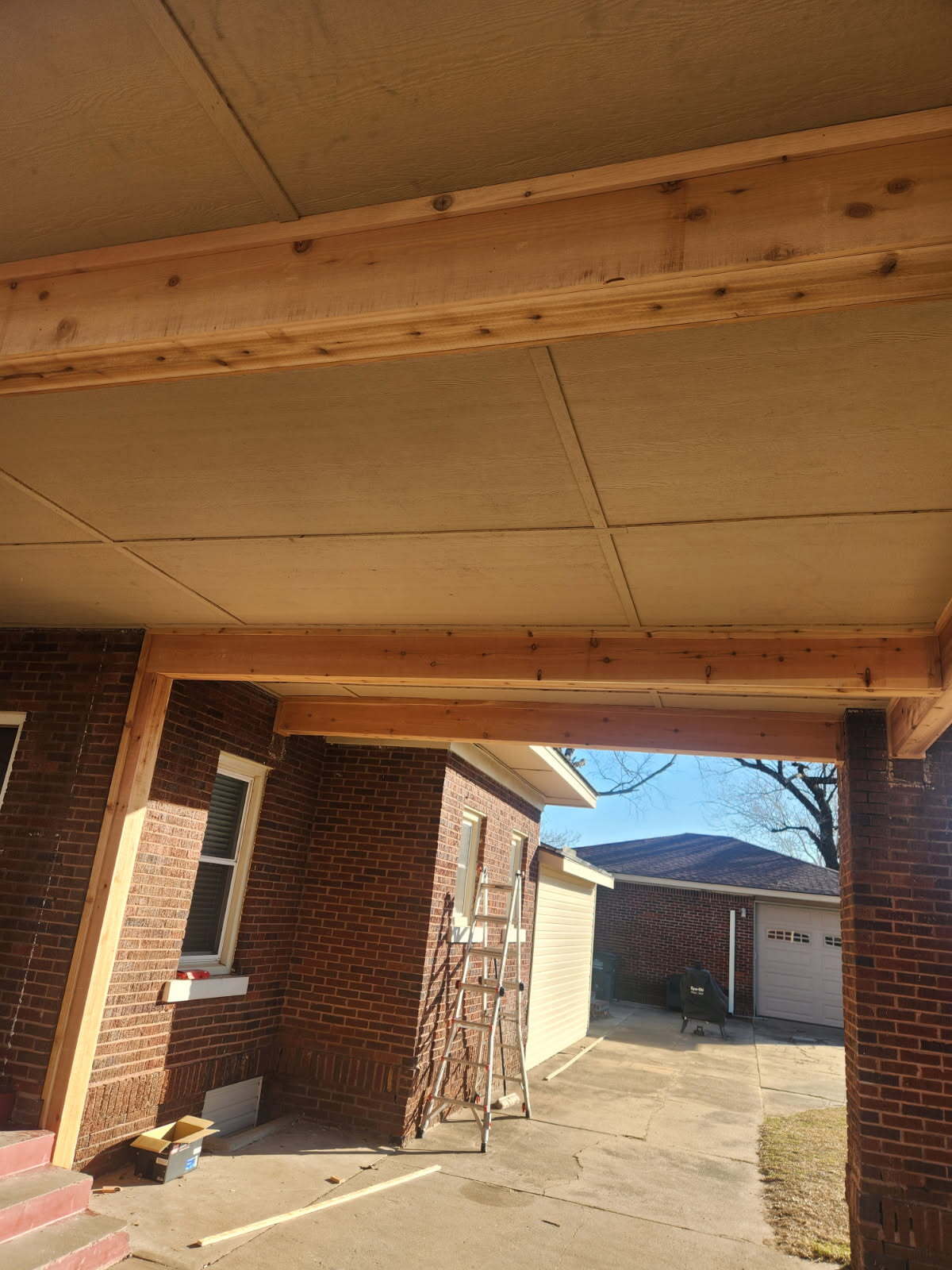 Wood beams and ceiling over driveway at brick house, crawlspace foundation